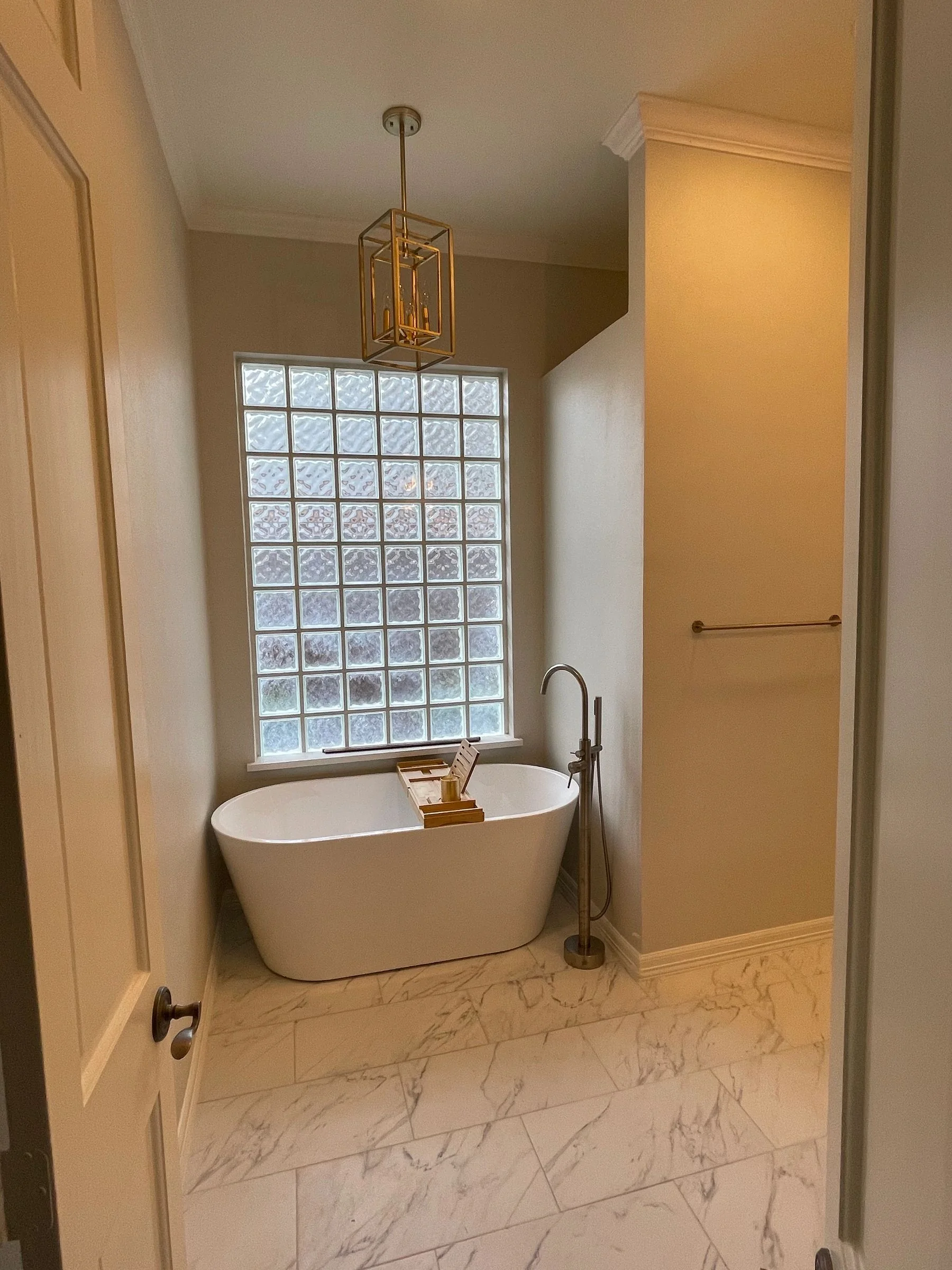 Bathroom finish with freestanding tub and glass-block window