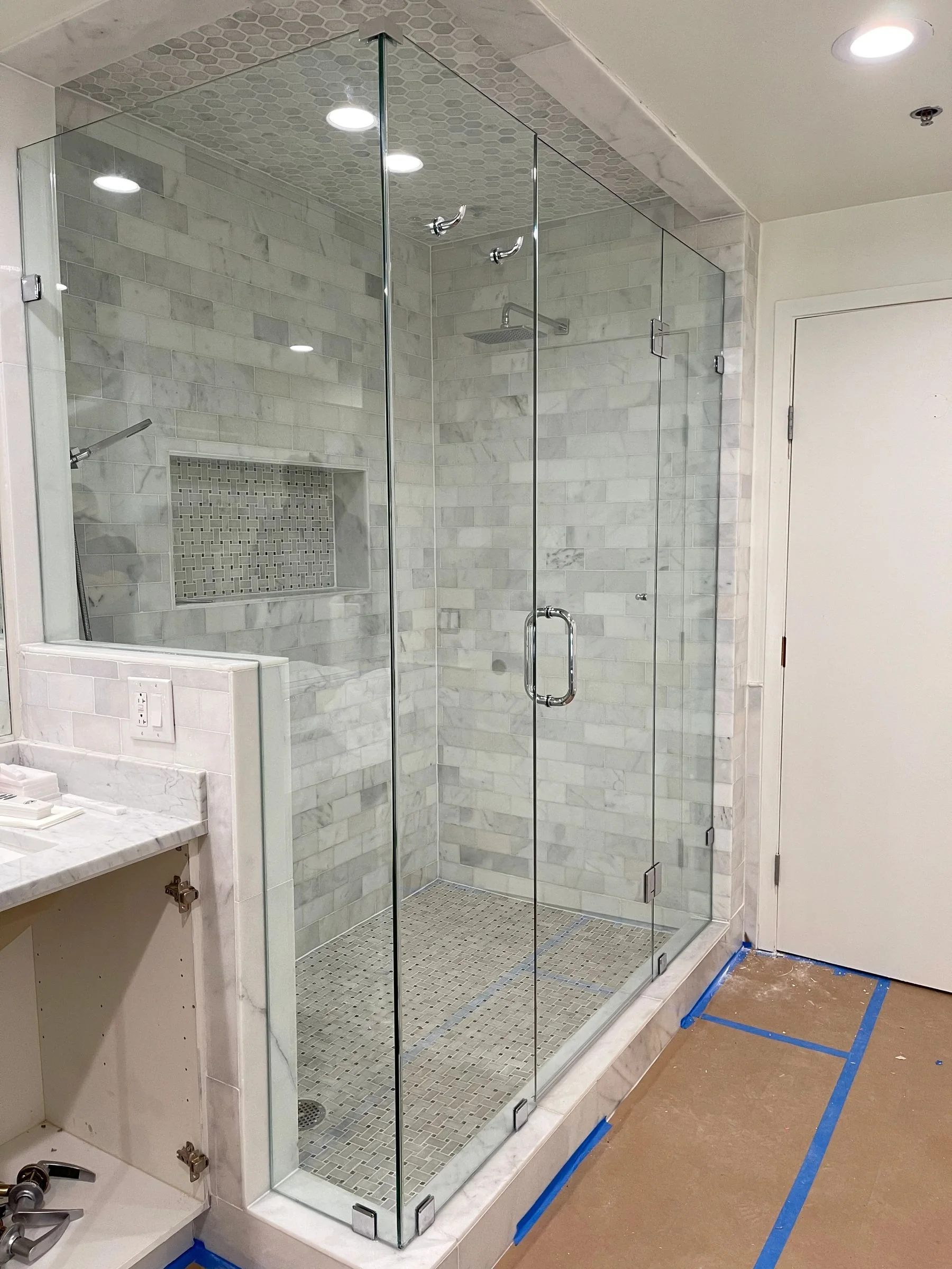 Glass shower with marble-look tile and finished vanity