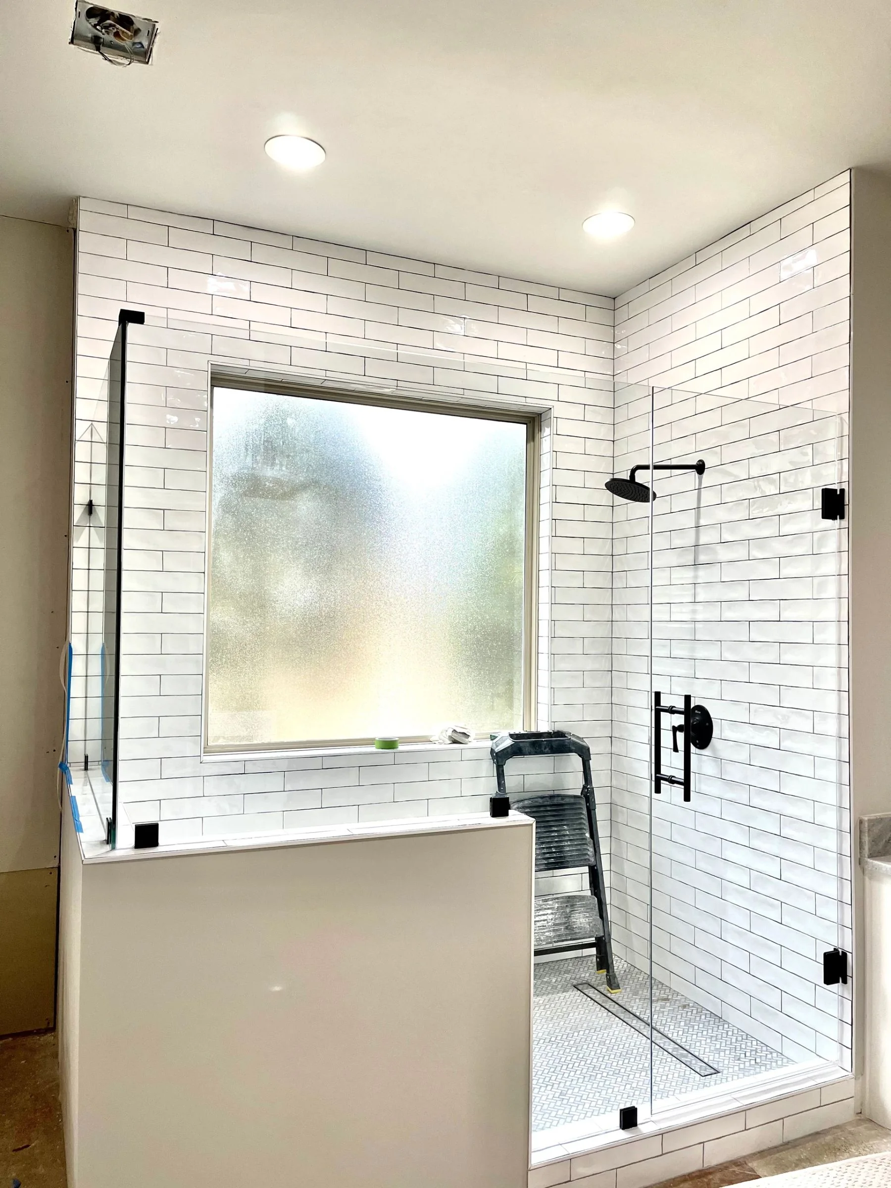 White tile shower with black fixtures and glass enclosure